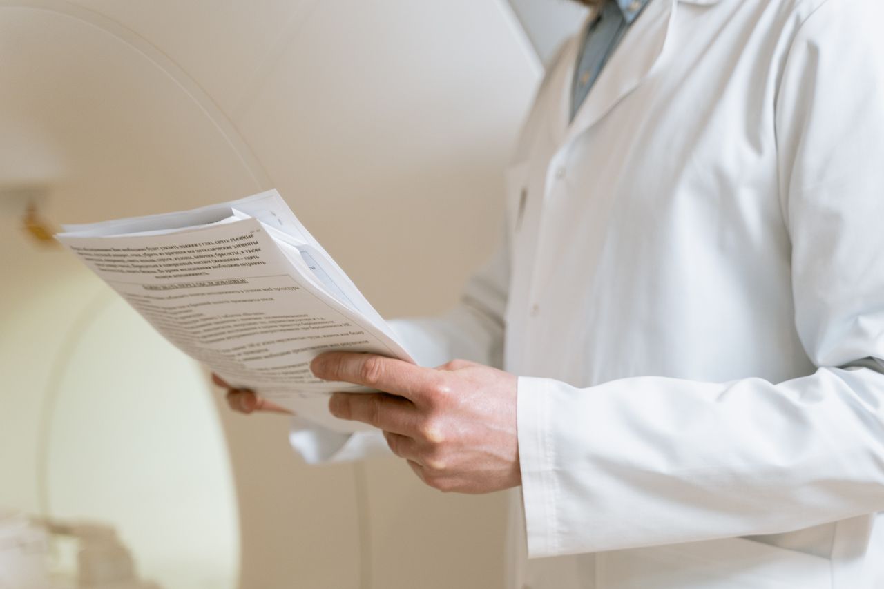 Home Doctor in a white coat examining medical papers in a healthcare setting.